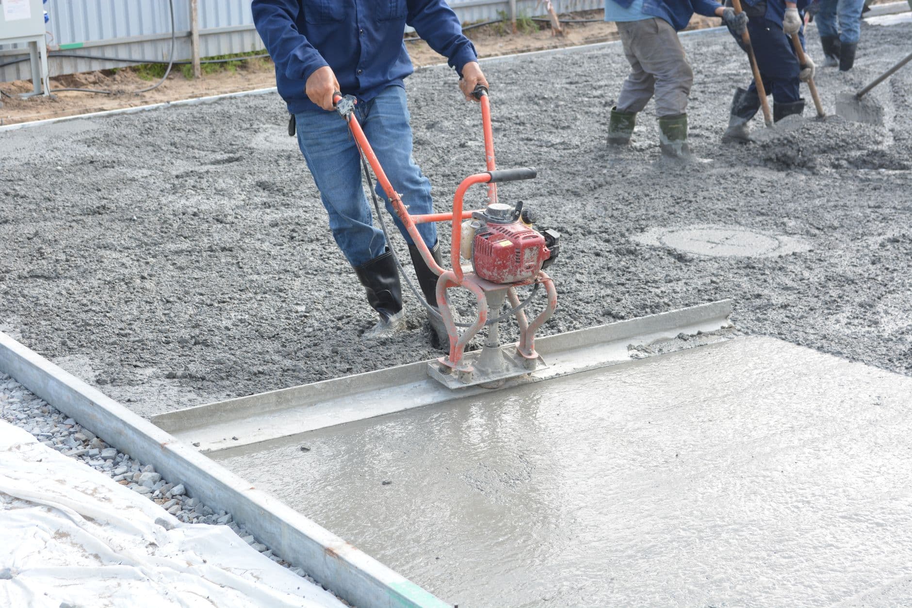 A crew finishing a fresh concrete slab with a power screed.